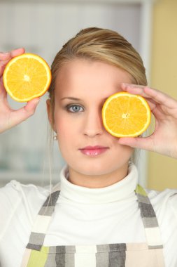 Woman holding orange halves to her face clipart