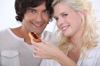 Woman feeding her boyfriend a biscuit clipart