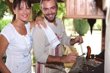 Couple cooking sausages on the barbecue clipart