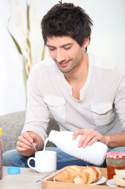 Man having breakfast on the sofa clipart