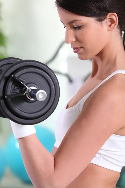 Młoda kobieta robi biceps loki w siłowni — Zdjęcie stockowe