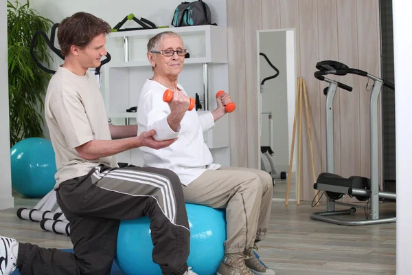 Yaşlı kadın spor salonunda kişisel bir eğitmen ile çalışma — Stok fotoğraf