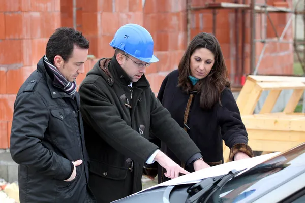 Architecte examinant un plan de construction avec ses clients — Photo