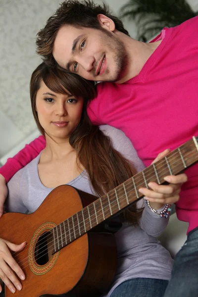 Dívka a chlapec s kytarou na gauči — Stock fotografie