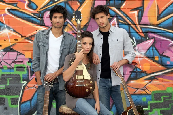 Three guitarists behind a tagged wall — Stock Photo, Image