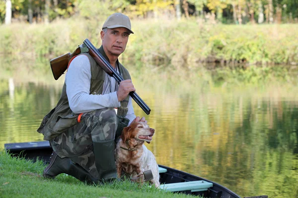 A hunter and his dog by a river. — Stock Photo, Image