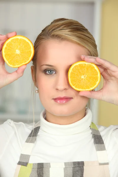 Женщина держит оранжевые половинки на лице — стоковое фото