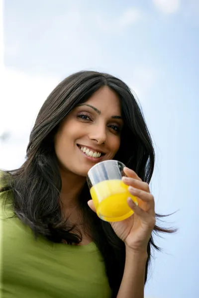 Kobieta na zewnątrz picie szklanki soku pomarańczowego — Zdjęcie stockowe