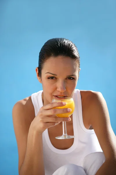 Morena bebendo suco de laranja de copo de vinho — Fotografia de Stock