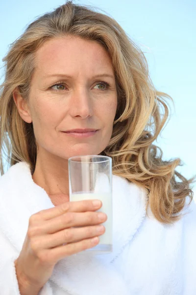 Женщина на улице в халате держит стакан молока — стоковое фото
