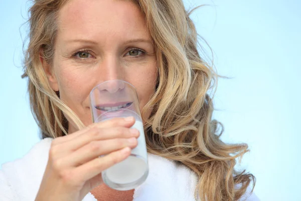 Nahaufnahme einer Frau im Bademantel, die ein Glas Milch trinkt — Stockfoto