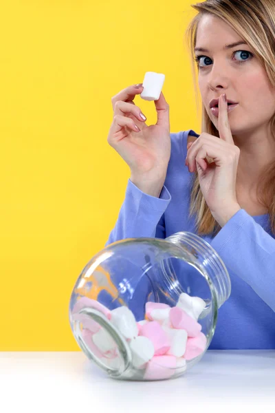 Женщина ест конфеты и делает знак молчания — стоковое фото
