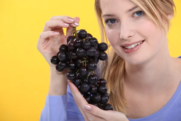 Una rubia linda sosteniendo uvas . — Foto de Stock