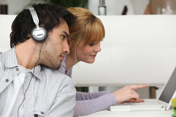 Jongen luisteren naar muziek en meisje met laptopcomputer — Stockfoto