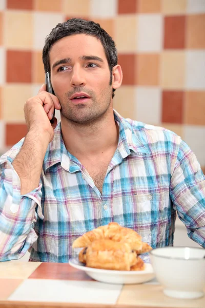 Мужчина, принимающий звонок за завтраком — стоковое фото
