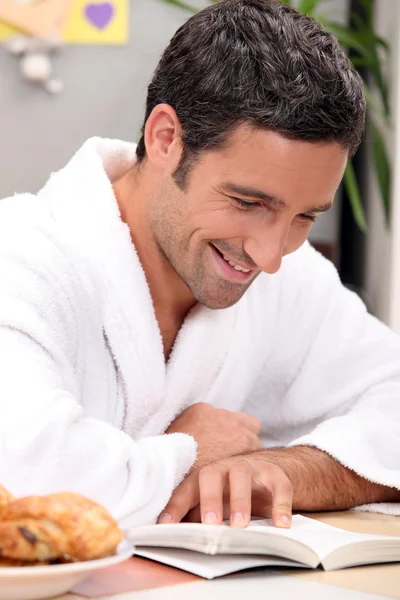 Hombre sonriente en bata leyendo —  Fotos de Stock