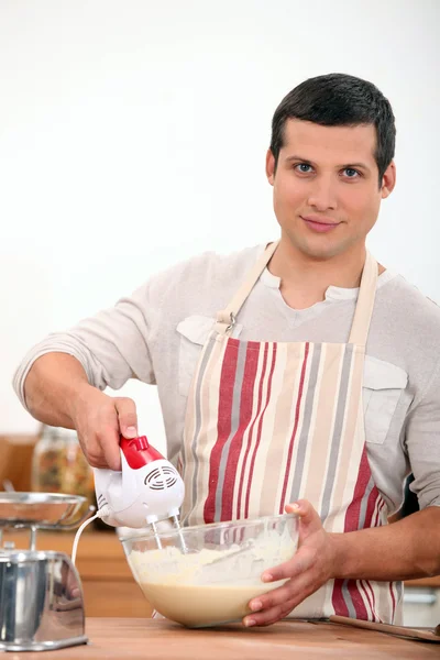 Young man using an electric egg beater — Stock Photo, Image