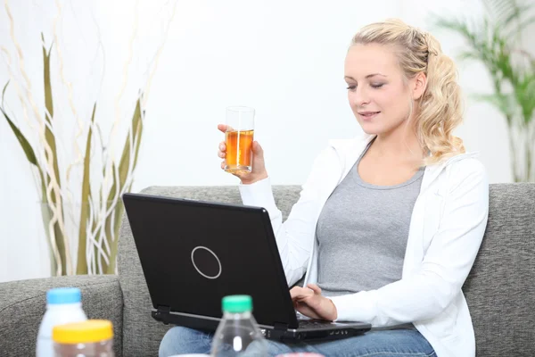 Frau surft im Internet und trinkt ein Glas Apfelsaft — Stockfoto
