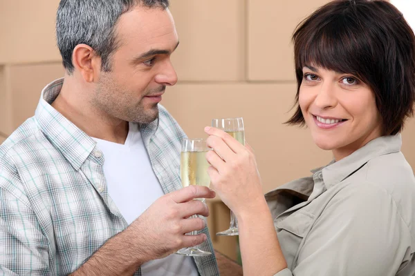 Couple drinking champagne in front of a pile of cardboard boxes — Stock Photo, Image
