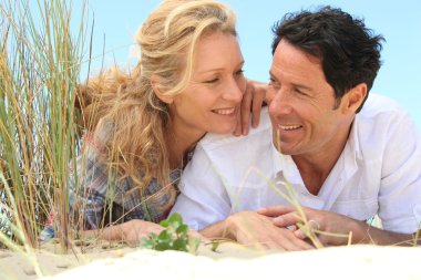 Couple looking into each other's eyes on the sand. clipart