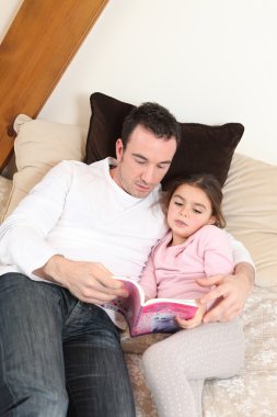 Father reading his daughter a story clipart