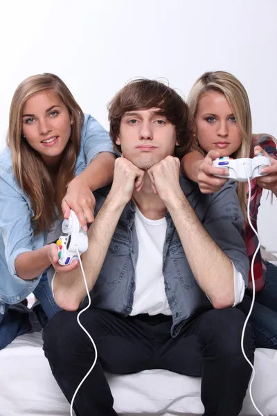 Znudzony nastolatek siedział między dwóch przyjaciół, grając w gry wideo — Zdjęcie stockowe