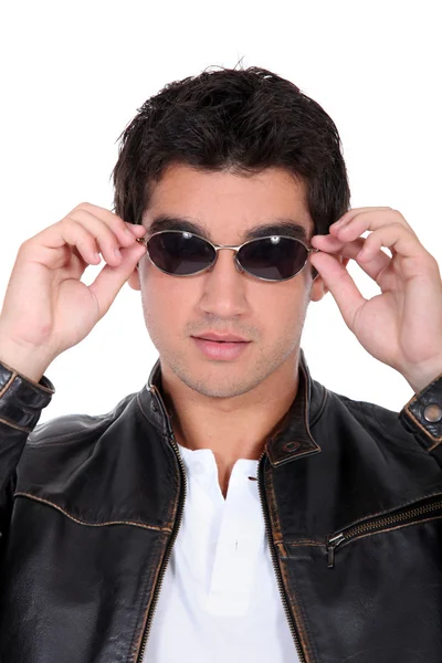 Bonito homem usando jaqueta de couro e óculos de sol — Fotografia de Stock
