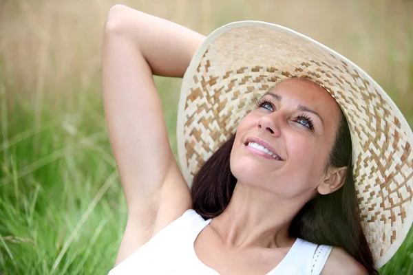 Woman wearing hat laid in field — Stock Photo, Image
