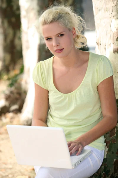 Блондинка в парке с ноутбуком — стоковое фото