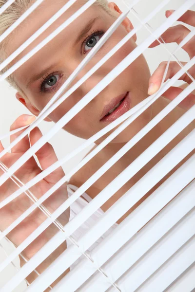 Mujer mirando a través de algunas persianas — Foto de Stock