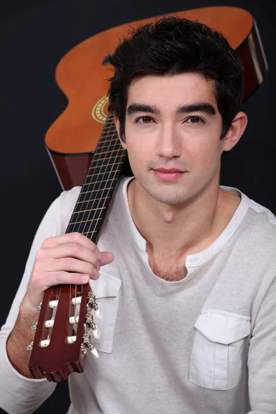 Young man holding a guitar on his shoulder — Stock Photo, Image