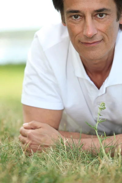 Man smiling laid on the grass — Stock Photo, Image