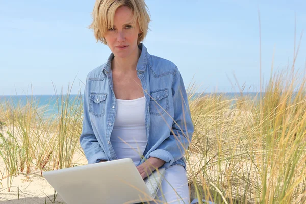Женщина на пляже с ноутбуком — стоковое фото