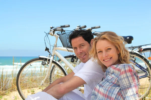 Couple on holiday sitting in front of bicycles — Stock Photo, Image