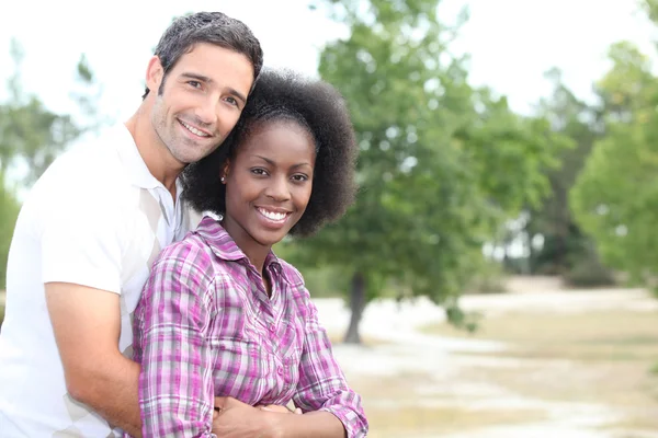 Mixed race couple hugging in the countryside — Stock Photo, Image