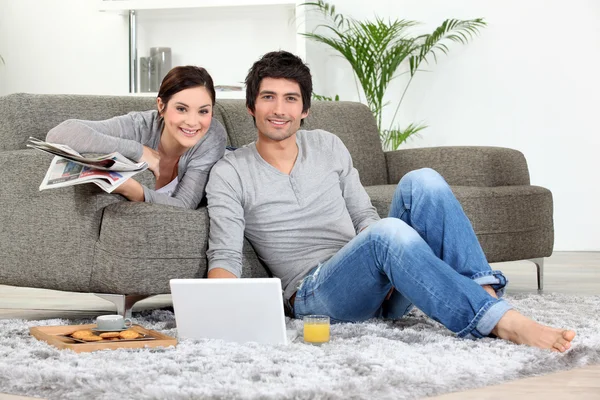 Para siedział na kanapie z laptopa i gazety — Zdjęcie stockowe