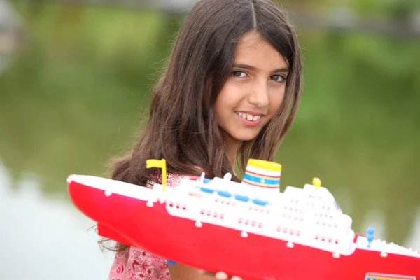 Junges Mädchen mit einem Spielzeugboot an einem See — Stockfoto