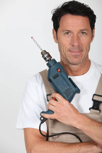 A smiling man holding a hammer drill and looking at us. — Stock Photo, Image