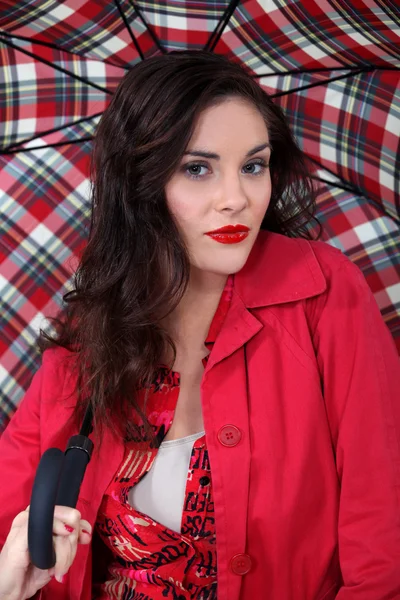 Γυναίκα με κόκκινο χρώμα με μια ομπρέλα ταρτάν — Φωτογραφία Αρχείου