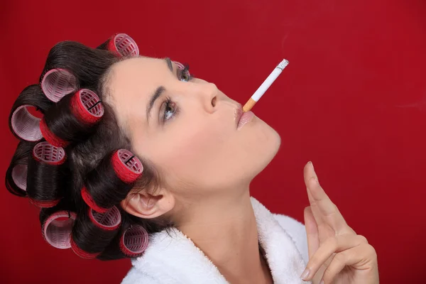 Курящая женщина с волосами в роликах — стоковое фото