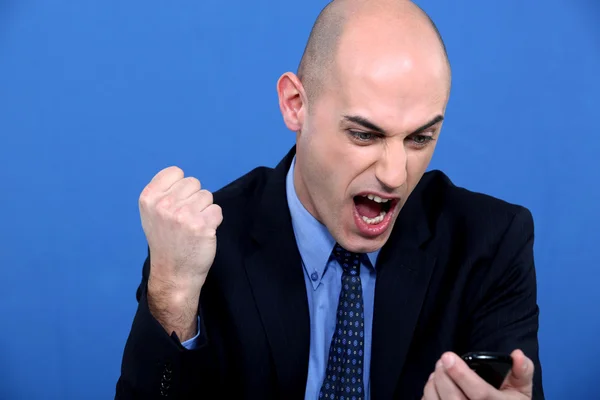Angry bald businessman holding telephone — Stock Photo, Image
