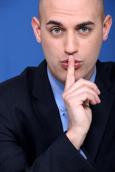 Hombre sosteniendo un dedo a sus labios — Foto de Stock