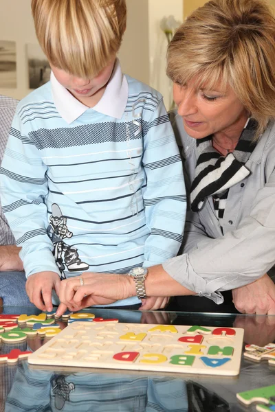 Grandmother helping her grandson with a puzzle — Stock Photo, Image