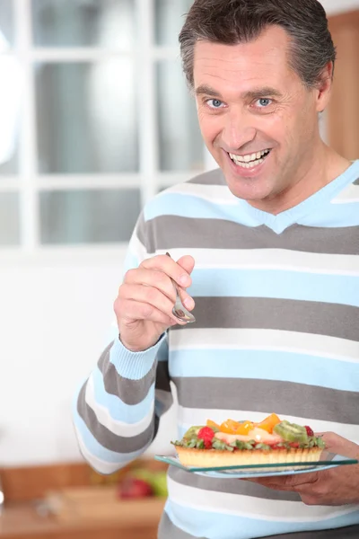 Lächelnder Mann isst eine Fruchtflan — Stockfoto