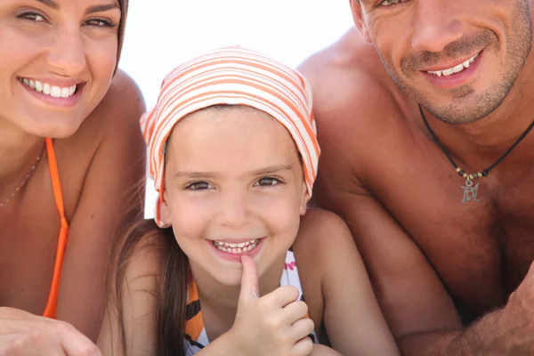 Young girl lying between her parents on the beach — Stock Photo, Image