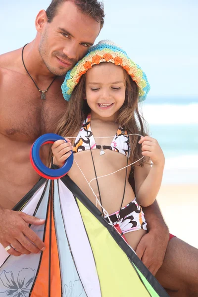 Pai e filha voando um papagaio em uma praia — Fotografia de Stock