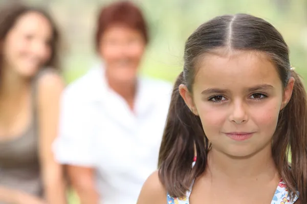 バック グラウンドで家族と一緒に立っていた若い女の子 — ストック写真