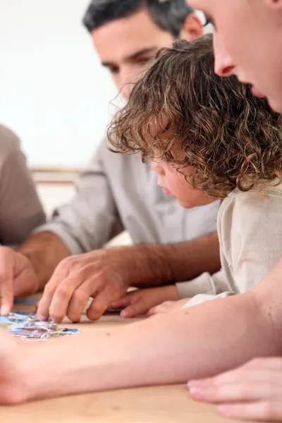 Família completando quebra-cabeças em casa — Fotografia de Stock