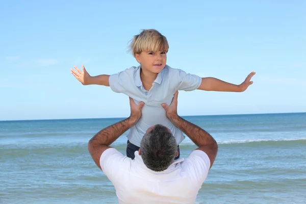 一个父亲背他的儿子在海滩. — 图库照片