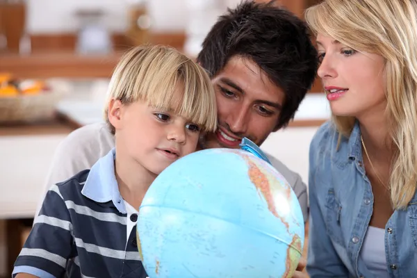 Família jovem olhando para um globo — Fotografia de Stock